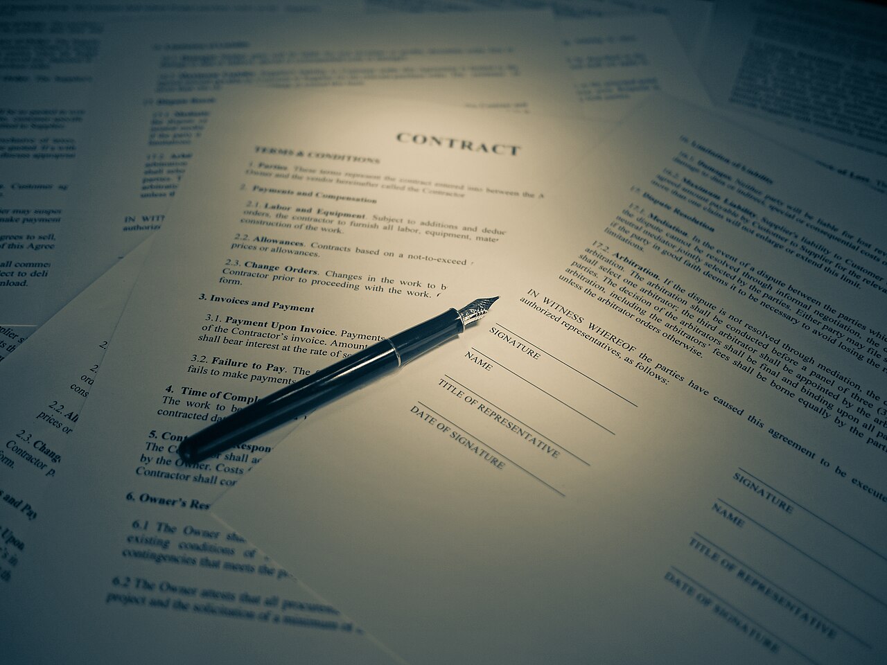 A pen resting on the signature line of a printed legal contract
